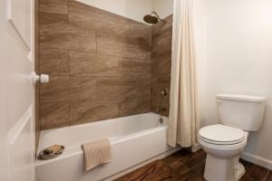 a bathroom with a toilet and a bath tub with a shower curtain at Garland Inn & Suites near Dallas TX in Garland