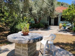 a stone table and two white chairs in a yard at Our Summer Nest in Panormos Skopelos