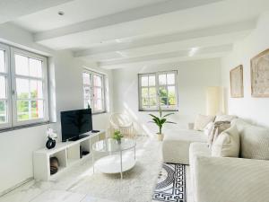 a white living room with a couch and a tv at Appartement "Hörnli Seeliebe" in Kreuzlingen