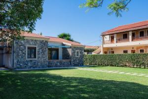 a house with a yard in front of a building at Villa Afroditi by Bostonia Village in Almiros Beach