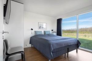 a bedroom with a bed and a large window at 1166-Ringkobing-Havstien-388 in Søndervig