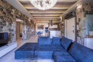 a living room with a blue couch and a stone wall at Villa Afroditi by Bostonia Village in Almiros Beach