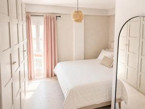 a white bedroom with a white bed and a window at Beach Apartment in Torre del Mar in Torre del Mar