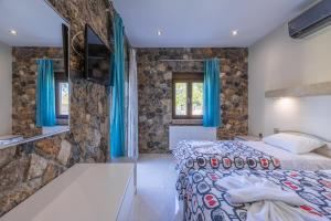 a bedroom with a bed and a stone wall at Villa Afroditi by Bostonia Village in Almiros Beach +33 photos
