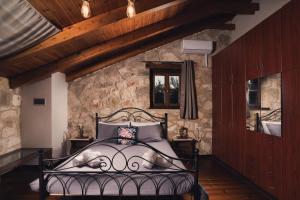 a bedroom with a black bed in a stone wall at Kidóni Villas in Gaïtánion