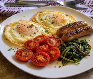 a plate of eggs and sausage and tomatoes on a table at Hotel Grand Paul in New Delhi