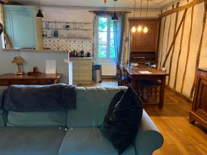 a living room with a blue couch and a kitchen at Chez Katia in Semur-en-Auxois