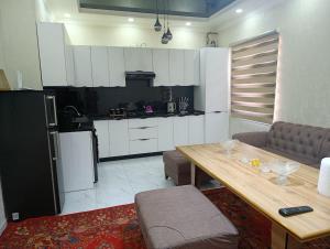 a kitchen with white cabinets and a wooden table in a room at comfort house in Khiva