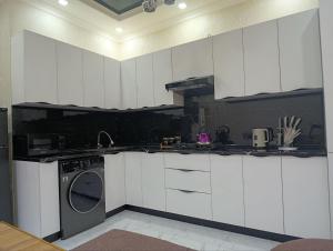a kitchen with white cabinets and a washing machine at comfort house in Khiva