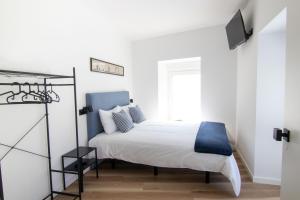 a white bedroom with a bed with a blue headboard at Latitude Guest House in Cantanhede