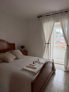 a bedroom with a bed with white sheets and a window at Casa do medio in Corcubión