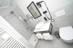 a white bathroom with a sink and a toilet at Hotel Villa Nord Hamburg-Airport in Hamburg