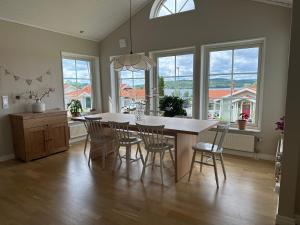 a dining room with a table and chairs and windows at House close to the forest and the lake in Huskvarna