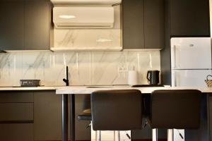 a kitchen with a counter with chairs and a refrigerator at Calliroe Sea View in Alexandroupoli +38 photos