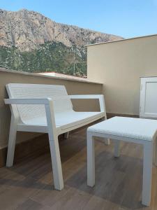 a white chair and bench on a balcony with a mountain at Maiori Vacation Home in Cinisi