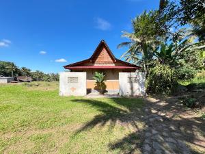 a small building with a sign in the grass at Omah Osing Ijen Banyuwangi in Licin