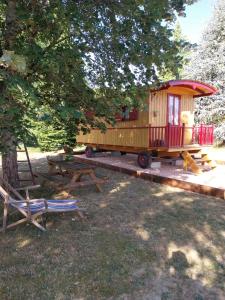 a wooden train car sitting next to a picnic table and a tree at La Roulotte de piégut in Piégut-Pluviers