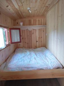 a bed in a wood paneled room in a cabin at La Roulotte de piégut in Piégut-Pluviers