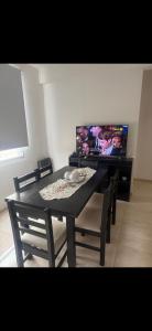 a dining room table with chairs and a flat screen tv at Acordes de Gaitas - Departamento 2 in Malargüe