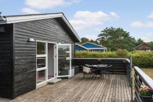 a black house with a deck with a table at C11241-Hemmet-Ildervej-22 in Hemmet