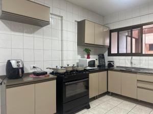 a kitchen with a stove top oven in a kitchen at Apartamentos nadai apto 202 in Foz do Iguaçu