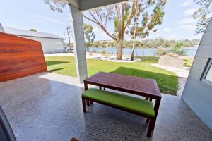 a wooden bench with a green seat on a porch at Waterfront Apartments in Devonport