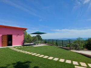 a large yard with a pink building and an umbrella at Villa Shtëpia në Pyll in Draç