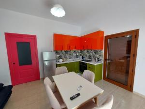 a kitchen with a table and a red door at Villa Shtëpia në Pyll in Draç +13 photos