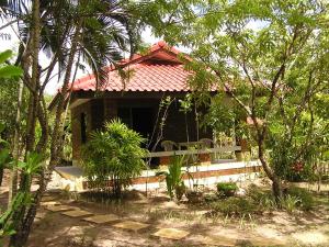 a small house with a red roof in a forest at Khoom Kam Kaew in Phrao
