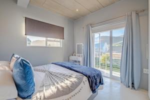 a bedroom with a bed and a large window at Meraki Sands in Hermanus