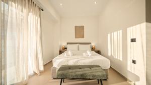 a white bedroom with a bed and a green ottoman at Ormos Piraeus in Piraeus