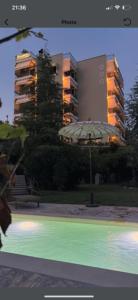 a building with an umbrella and a bench in a park at Sagini Hotel in Loutra Edipsou