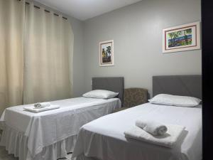 two beds in a room with towels on them at Apartamentos nadai apto 202 in Foz do Iguaçu