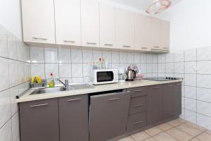 a kitchen with white cabinets and a sink and a microwave at Apartmants 38 in Pag +17 photos