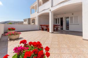 a patio with red flowers in front of a building at Apartmants 38 in Pag