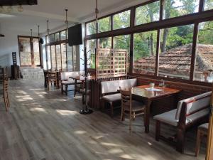 a restaurant with wooden tables and chairs and windows at Gorna Kukja Apartments in Demir Hisar