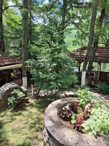 a garden with a stone planter with flowers and trees at Gorna Kukja Apartments in Demir Hisar