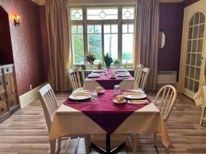 a dining room with a long table with red table cloth at Auberge La Seigneurie in Matane +12 photos