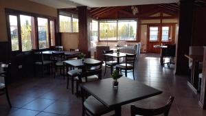 a restaurant with tables and chairs and windows at Hosteria Puerto San Julian in El Calafate