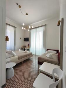 a hotel room with two beds and a table and chairs at Palazzo San Giorgio 1924 in Scilla