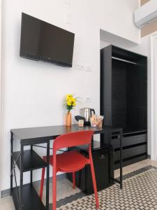 a black desk with a red chair and a tv on a wall at Palazzo San Giorgio 1924 in Scilla