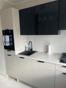 a white kitchen with a sink and a microwave at Apartament Rubinkowo in Toruń