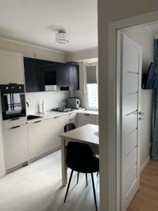 a kitchen with white cabinets and a table with a chair at Apartament Rubinkowo in Toruń