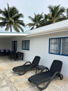 a group of chairs sitting on a patio with palm trees at Hildas Villa in Arorangi