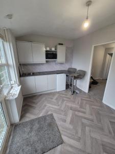 a kitchen with white cabinets and a wooden floor at Seascape Spa Retreat in Niton