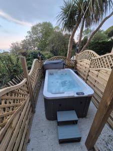 a hot tub sitting on a patio with two chairs at Seascape Spa Retreat in Niton +9 photos