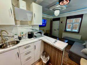 a kitchen with white cabinets and a sink and a couch at Blackpool cosy cottage in Blackpool +25 photos