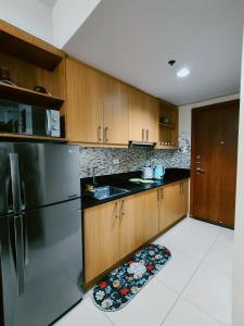 a kitchen with wooden cabinets and a stainless steel refrigerator at MOA shell residences - JOSH in Manila
