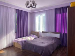 a bedroom with purple curtains and a bed and a window at Quiet house in Buknari