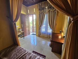 a bedroom with a bed and a desk and a window at Sumatra Inn & Travel in Bukit Lawang